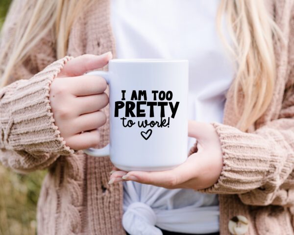 A person holding a coffee mug that says " i am too pretty to work ".