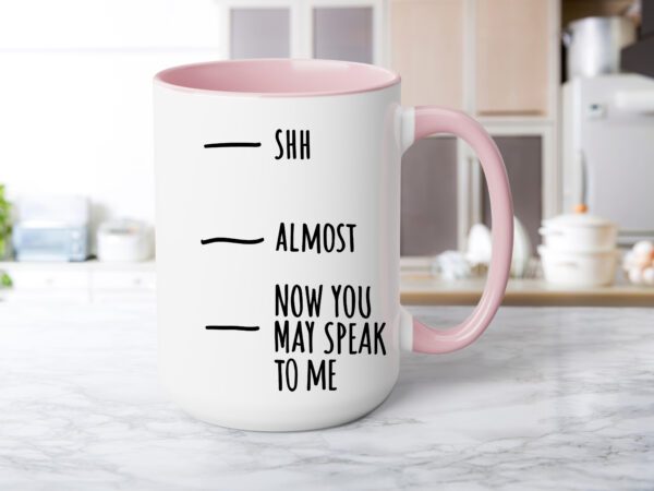 A pink coffee mug with the words shh almost and now you may speak to me.