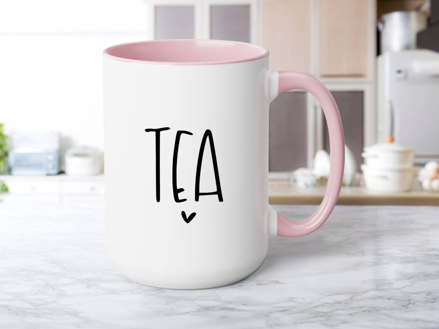 A pink coffee mug with the word tea written in black.