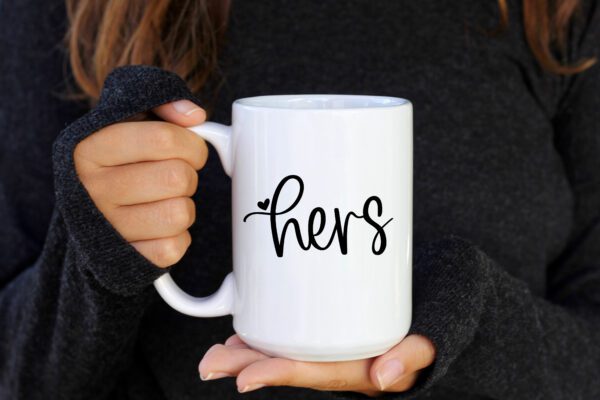 A person holding a coffee mug that says hers.