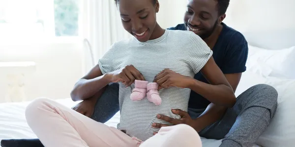 A woman is holding baby shoes while another person watches.