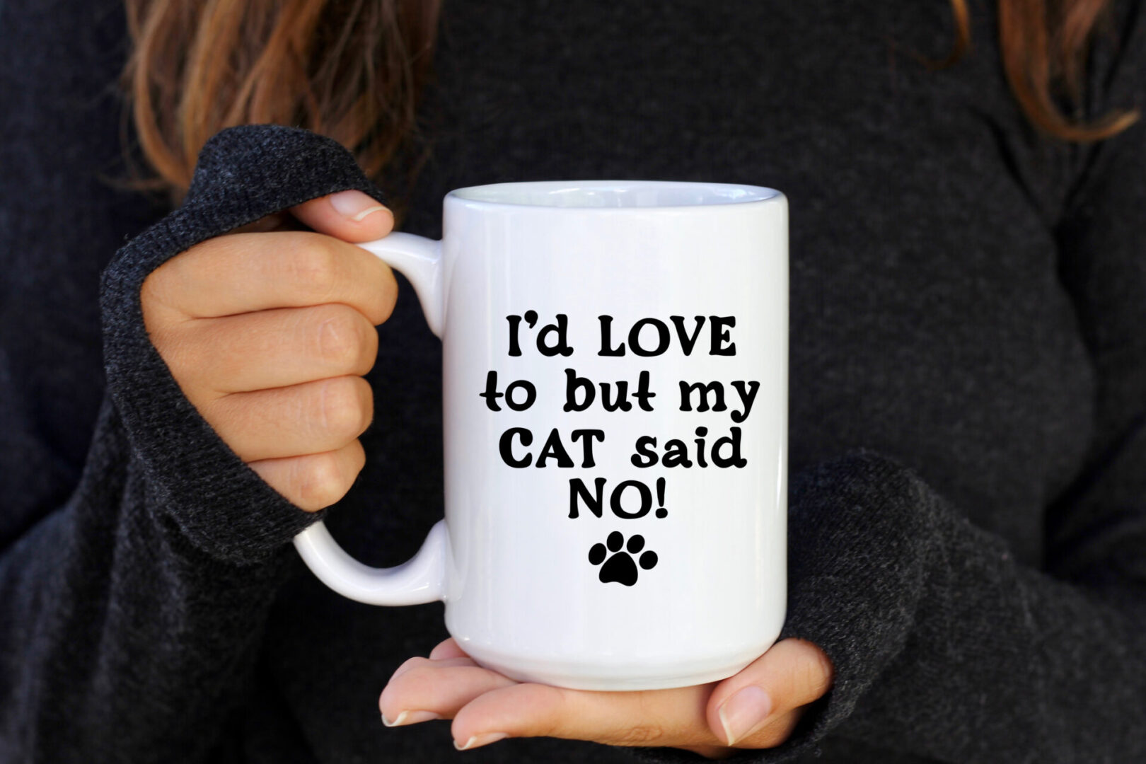 A person holding a coffee mug that says " i 'd love to but my cat said no ".