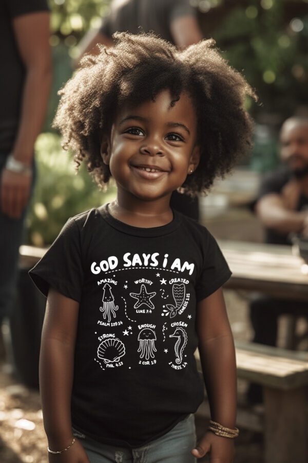 A young child wearing a t-shirt with the words " god says i am ".