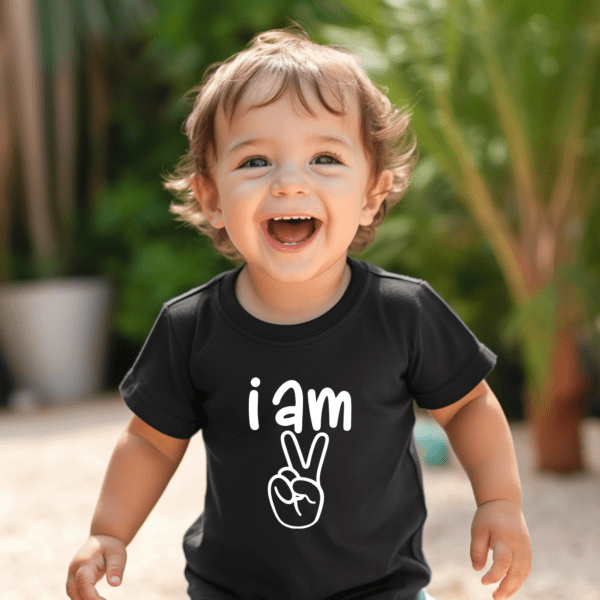 A young child is smiling and wearing a shirt with the words " i am peace ".