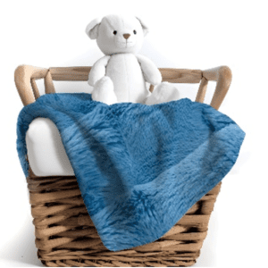 A teddy bear sitting in a basket with blue blanket.