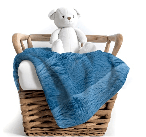 A teddy bear sitting in a basket with blue blanket.