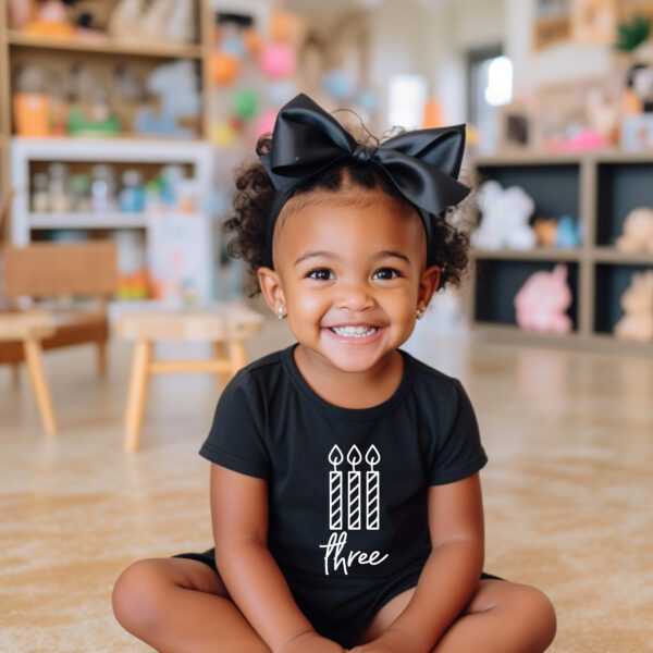 A little girl sitting on the ground wearing a black shirt